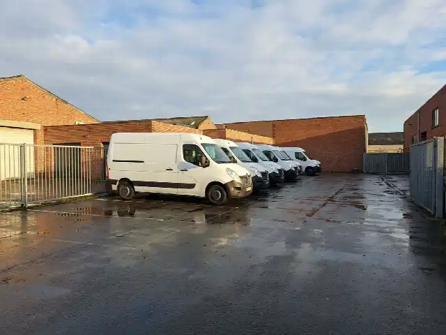 Rij witte bestelwagens op de parking van een bedrijf in de ochtend